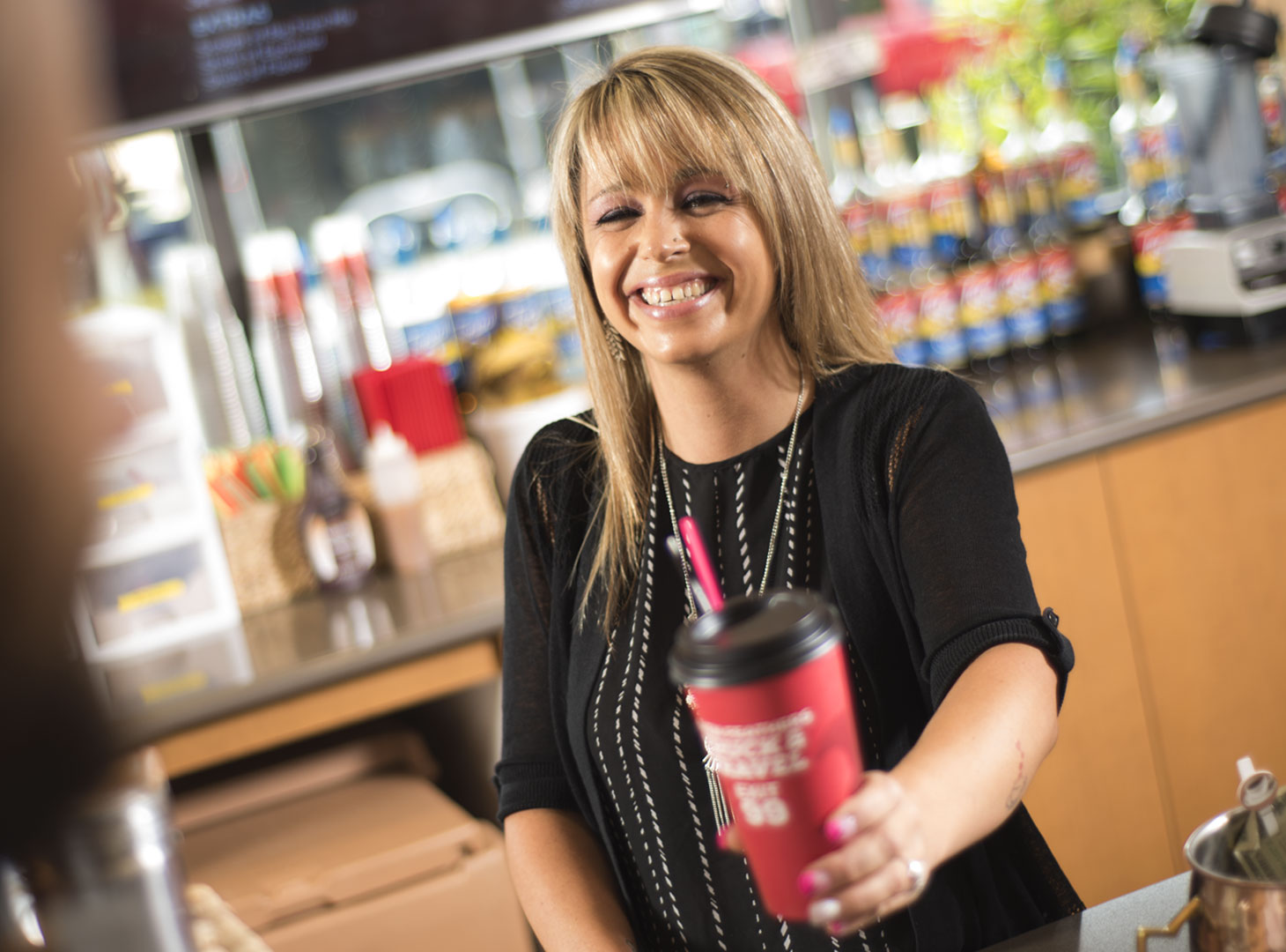 Barista handing an espresso drink to a customer.